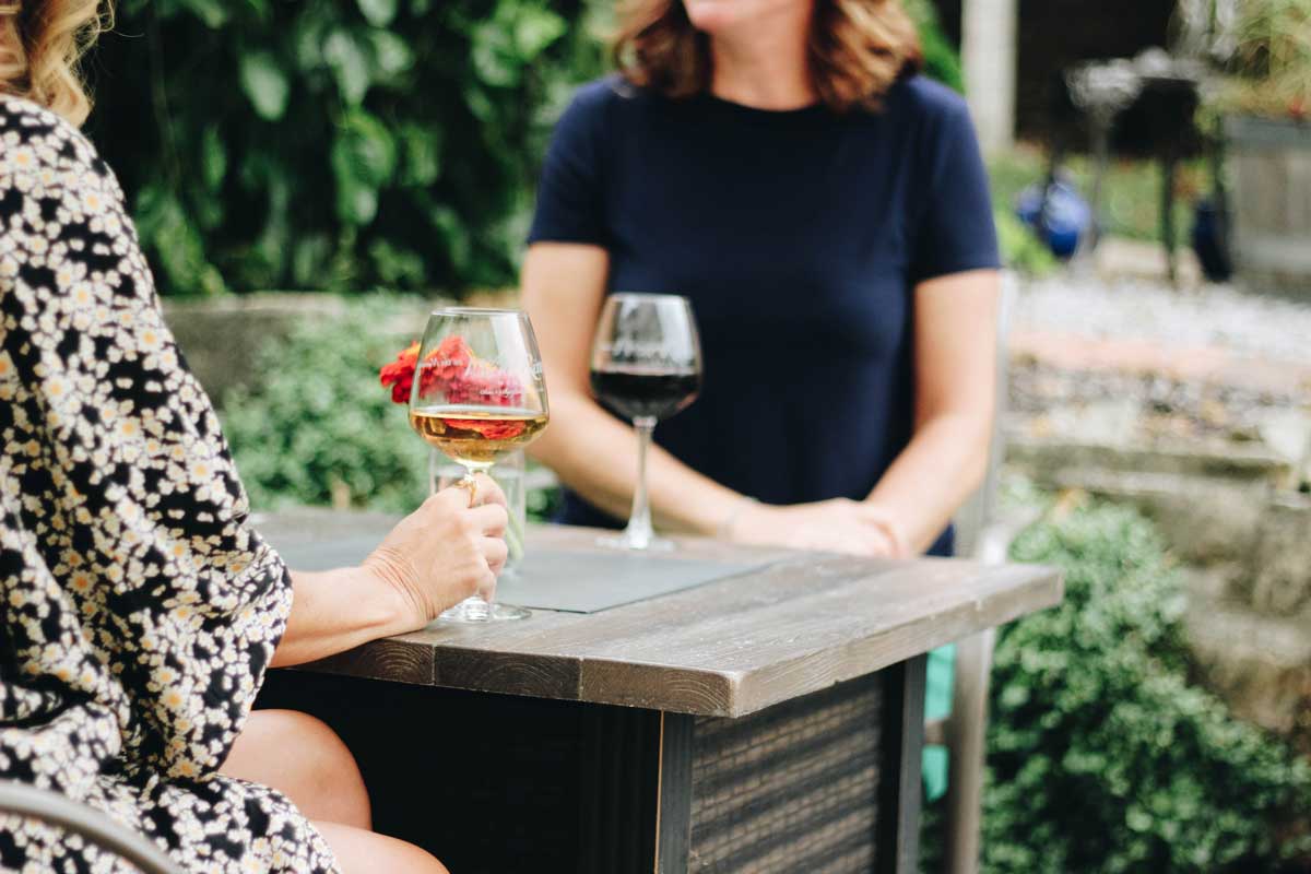 two women enjoying wine and chatting at an outdoor table